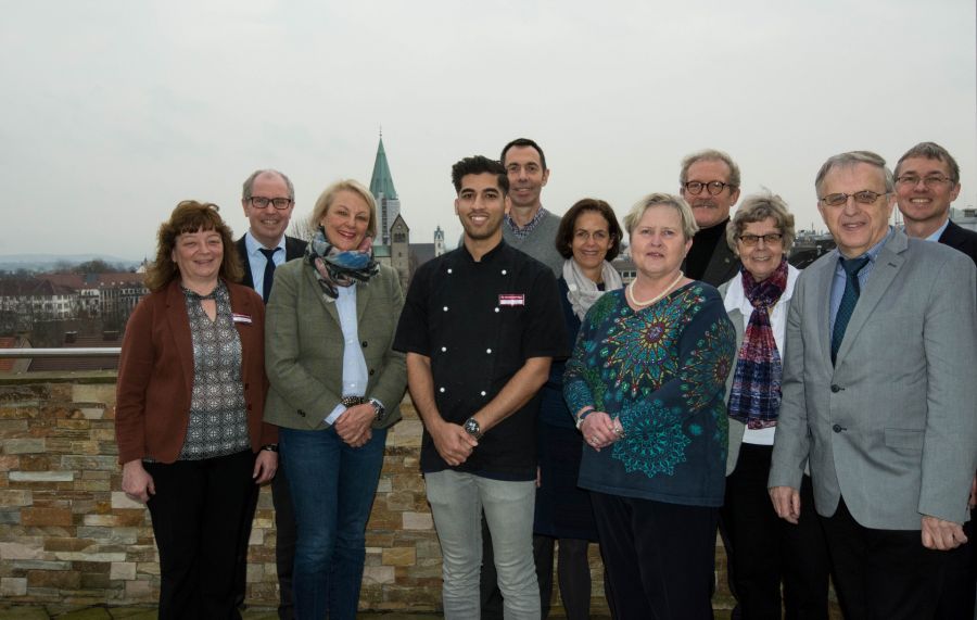Besuchten Auszubildenden Dawood Iqbal (Mitte in schwarzer Kochjacke) im Hotel (von links): Barbara Diehl (Ausbildungsleiterin), Landrat Manfred Müller, Babara Scholz – Bornhorst (Rotary Club Paderborn Stadt + Land), Michael Theobald (Ausbildungsakquisiteur), Petra Münstermann (Projektkoordinatorin, Bildungs- und Integrationszentrum), Ingrid Aspin (Praktikumsakquisiteurin), Ulrich Hilkenbach (Praktikumsakquisiteur), Gabriele Grewing (Praktikumsakquisiteurin), Herrmann Knaup (Praktikumsakquisiteur) und Dr. Oliver Vorndran (Leiter des Bildungs- und Integrationszentrums). (Foto: Amt für Presse- und Öffentlichkeitsarbeit, Kreis Paderborn, Anna-Sophie Schindler)